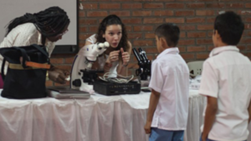MaríaDuque-Correa博士与两名接近桌子的年轻学生交谈