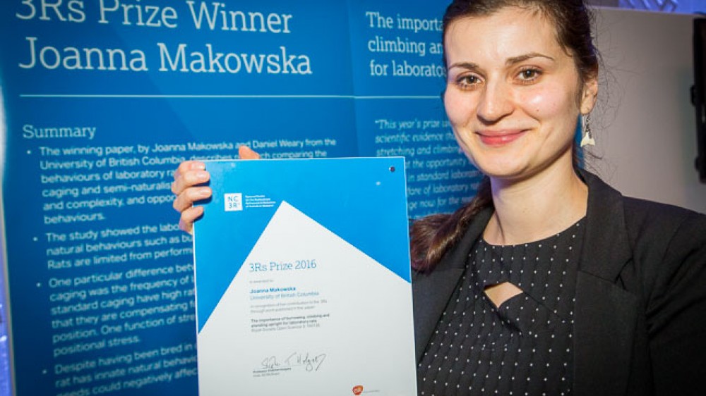2016年获奖者：Joanna Makowska博士。乔安娜（Joanna）在描述她作品的海报前面看到。她正在持有奖励证书。