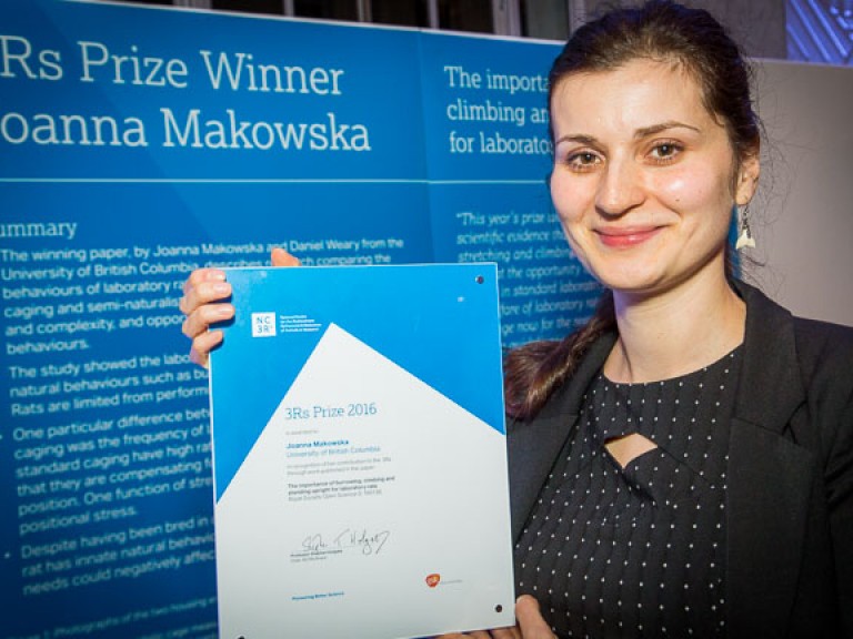 2016年获奖者:乔安娜·马科夫斯卡博士。乔安娜站在描述她工作的海报前。她高举着她的奖状。