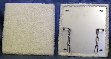 白色的羊毛板，一块显示羊毛的正面，另一块显示附着在灵长类动物围栏上的固定装置。