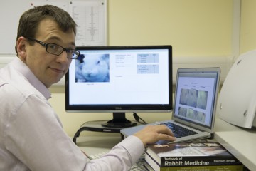 马特·里奇博士在笔记本电脑上的侧面照片，旁边有一个显示器